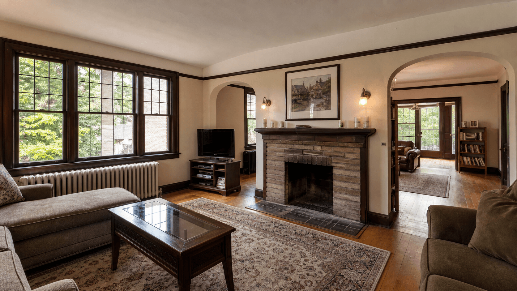 Tudor Revival 老房的分隔式客厅、砖壁炉、窄格窗、暖气片和拱形门洞室内示意图