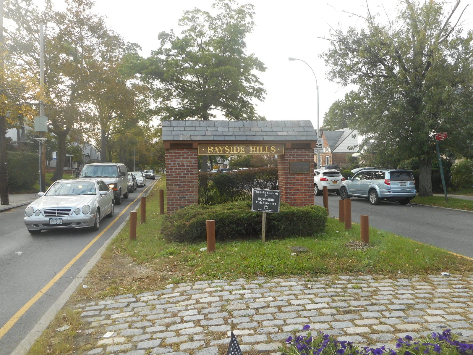Bayside南部住宅片区Bayside Hills的Bell Boulevard与48th Avenue入口，绿地、车辆和两侧住宅实景
