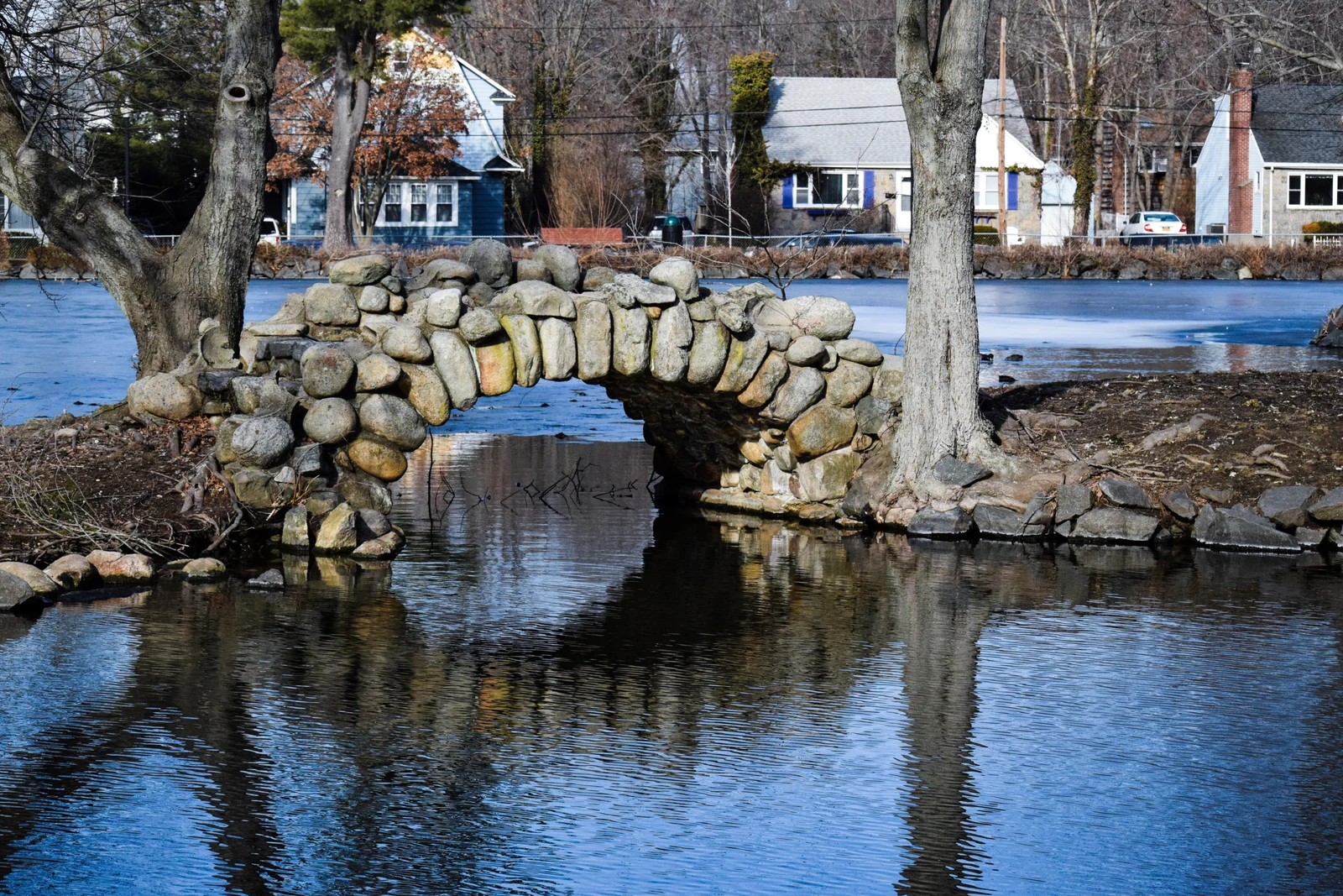 Huntington的Heckscher Park冬季池塘石桥与公园旁住宅