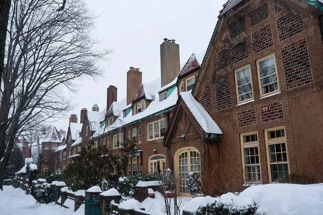 Forest Hills雪后的Tudor风格连排住宅、陡屋顶与树木街道