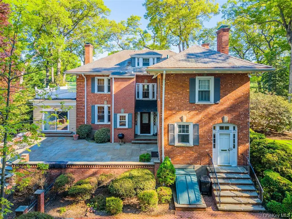 Rear exterior of the brick Colonial home and terrace