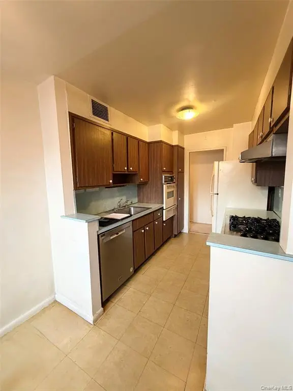Windowed kitchen with wood cabinetry and appliances