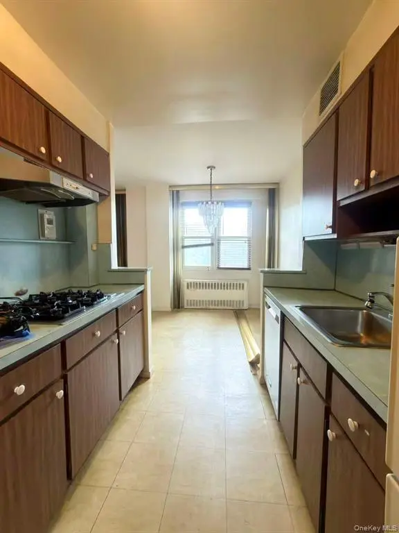 Windowed galley kitchen with wood cabinetry and appliances