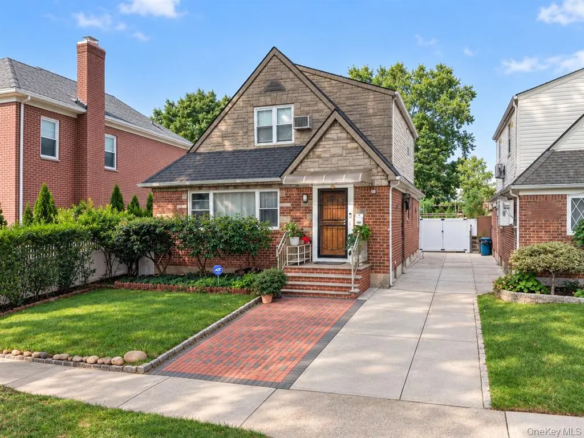 Front exterior of the detached brick Oakland Gardens home with private driveway