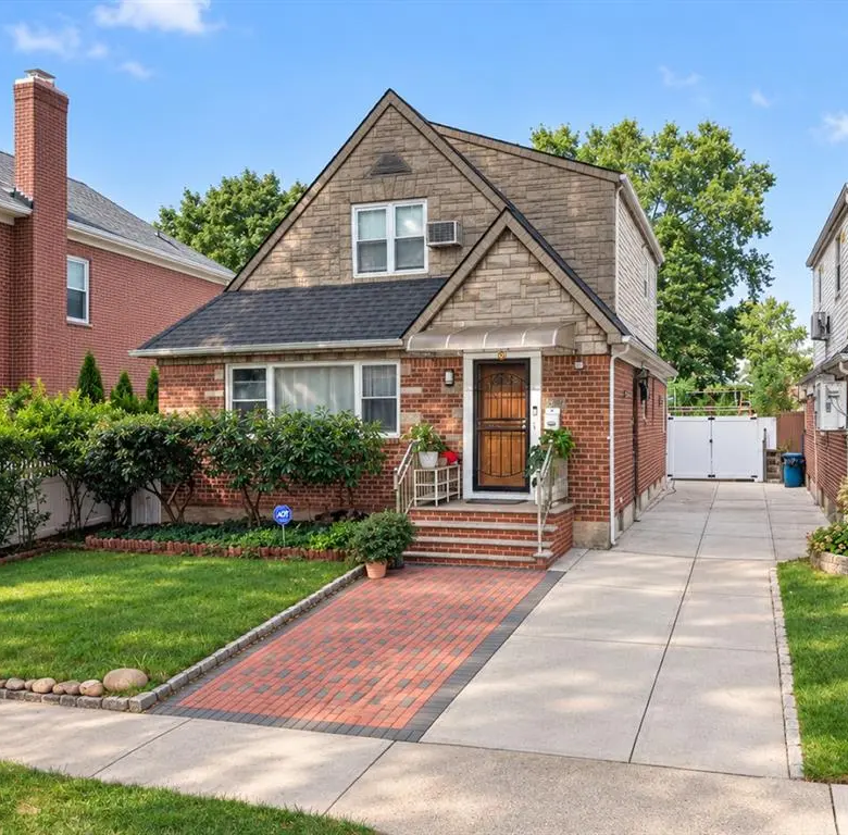 Front exterior of the detached brick Oakland Gardens home with private driveway
