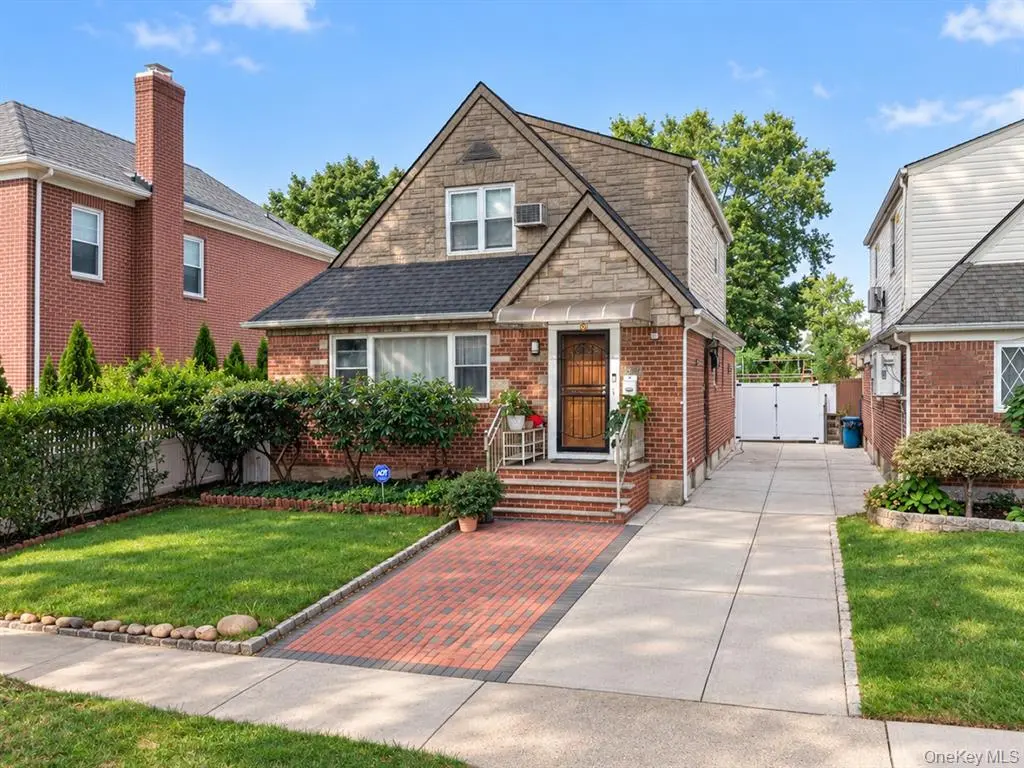 Front exterior of the detached brick Oakland Gardens home with private driveway