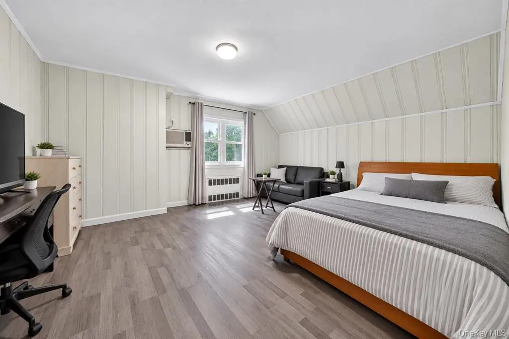 Bedroom with wide window and wood-look flooring