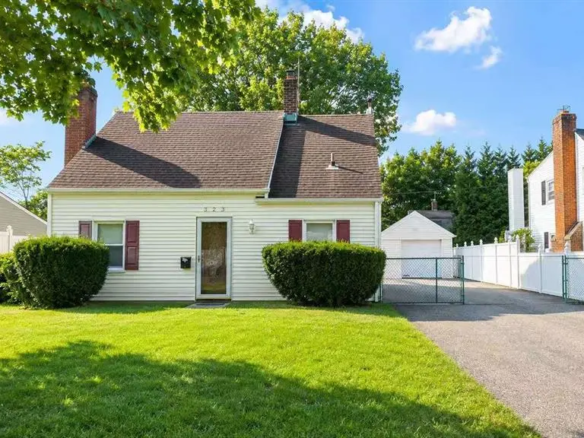 Front exterior of the Carle Place single-family home with driveway and detached garage