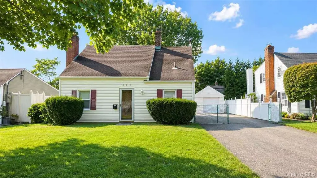 Front exterior of the Carle Place single-family home with driveway and detached garage