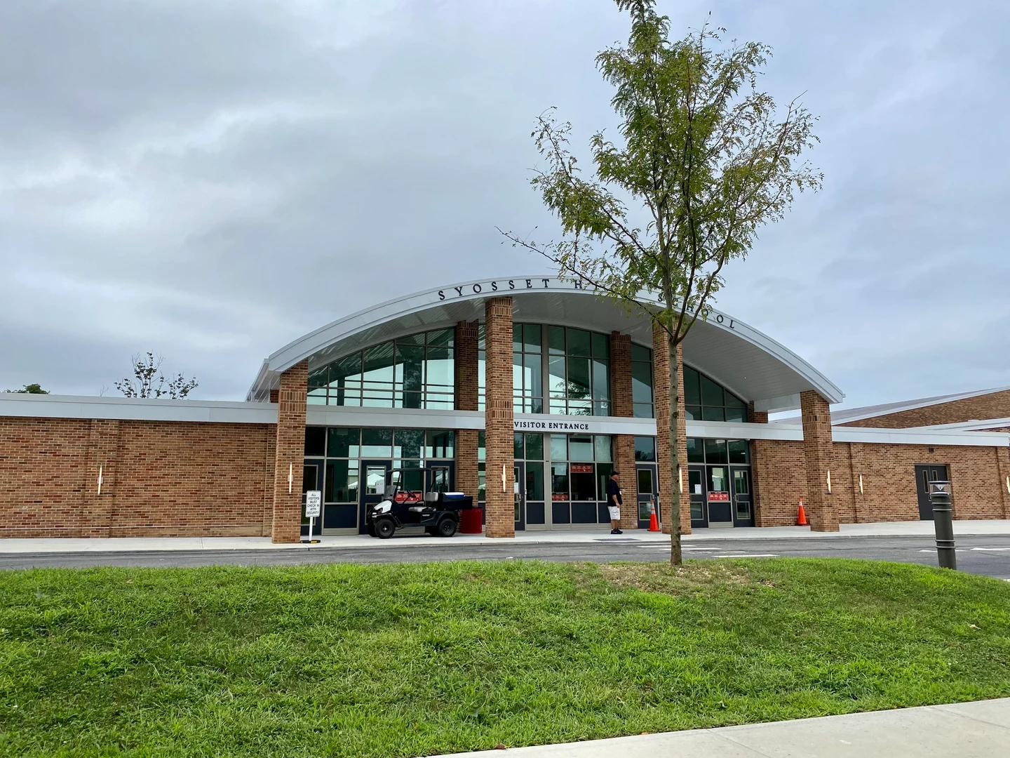 Syosset High School的砖墙玻璃入口、弧形门廊屋顶与前方草地